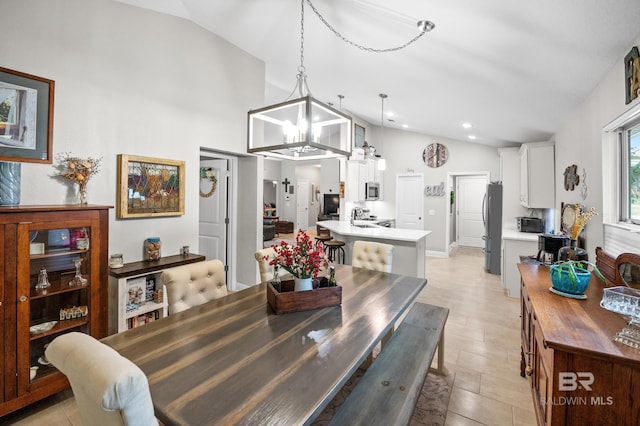 dining room featuring an inviting chandelier, high vaulted ceiling, and sink