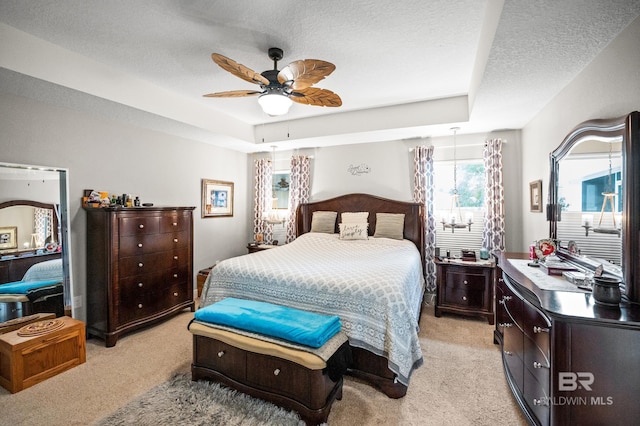 carpeted bedroom with ceiling fan, a raised ceiling, and a textured ceiling