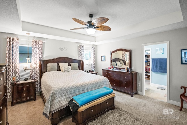 bedroom featuring ceiling fan, light colored carpet, a tray ceiling, and a textured ceiling