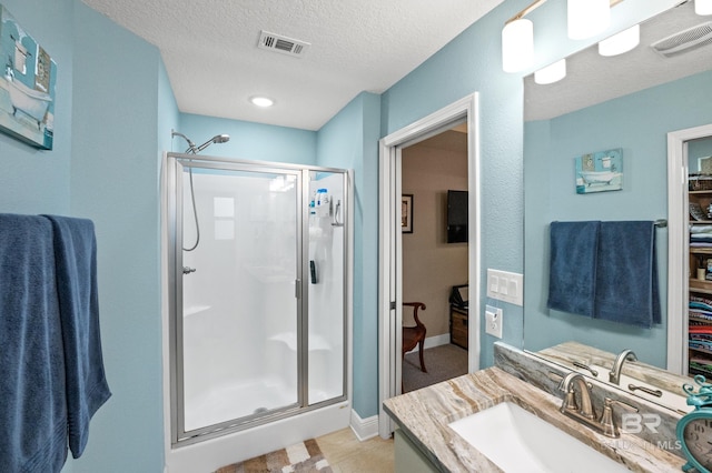 bathroom featuring vanity, an enclosed shower, and a textured ceiling