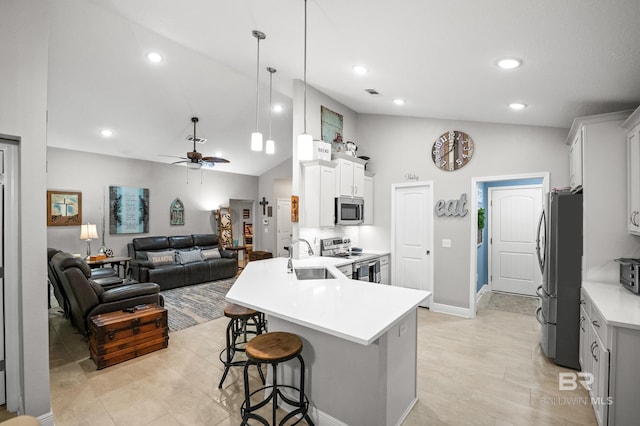 kitchen with sink, a breakfast bar area, white cabinetry, hanging light fixtures, and stainless steel appliances