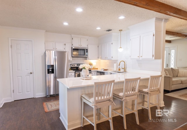 kitchen with appliances with stainless steel finishes, pendant lighting, white cabinetry, sink, and beam ceiling