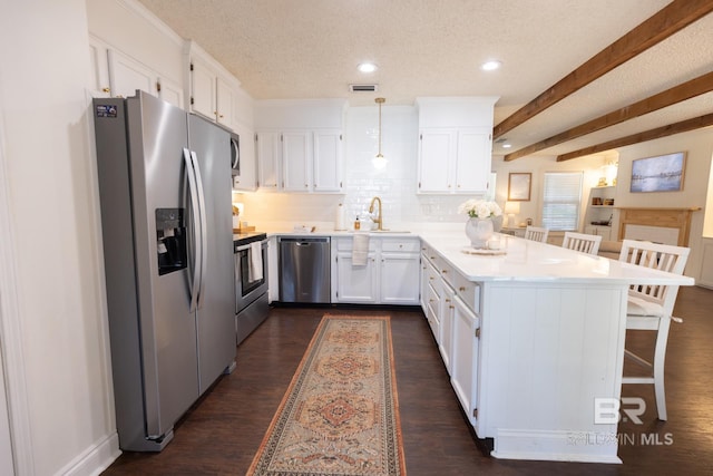 kitchen with white cabinetry, a kitchen breakfast bar, hanging light fixtures, stainless steel appliances, and a textured ceiling