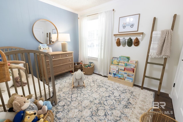 bedroom with dark hardwood / wood-style flooring, crown molding, and a nursery area