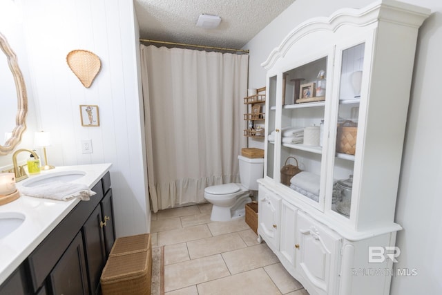 bathroom with wood walls, tile patterned flooring, vanity, toilet, and a textured ceiling