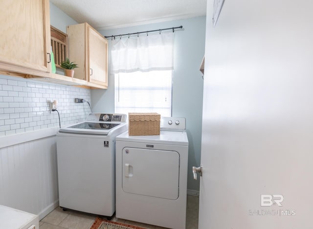 washroom with cabinets, light tile patterned floors, and washer and clothes dryer