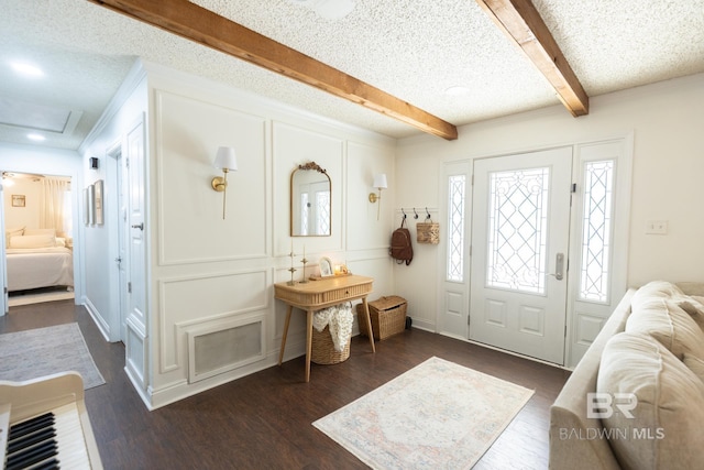 entryway featuring dark hardwood / wood-style flooring, a textured ceiling, and beam ceiling