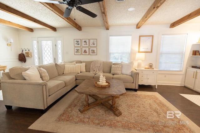 living room with beamed ceiling, ceiling fan, a textured ceiling, and dark hardwood / wood-style flooring