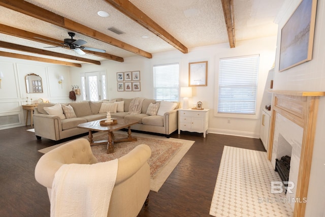 living room with dark wood-type flooring, a textured ceiling, and a wealth of natural light