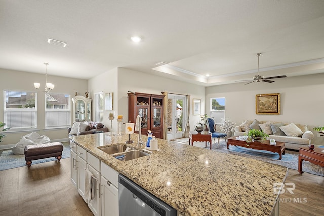 kitchen with sink, hanging light fixtures, a center island with sink, dishwasher, and white cabinets