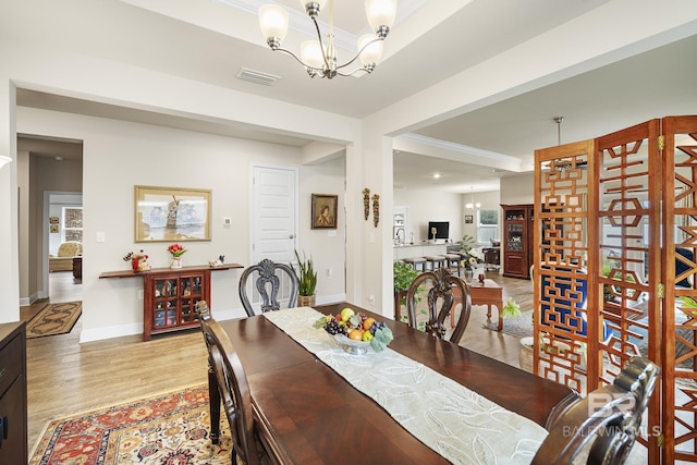 dining space featuring an inviting chandelier, crown molding, and light hardwood / wood-style flooring