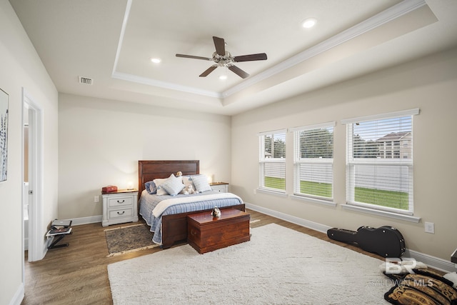 bedroom with a raised ceiling, dark hardwood / wood-style floors, and ceiling fan