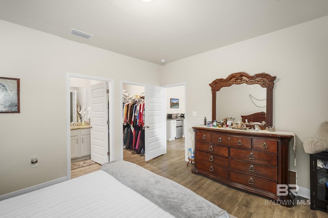 bedroom featuring connected bathroom, a walk in closet, light hardwood / wood-style floors, and a closet