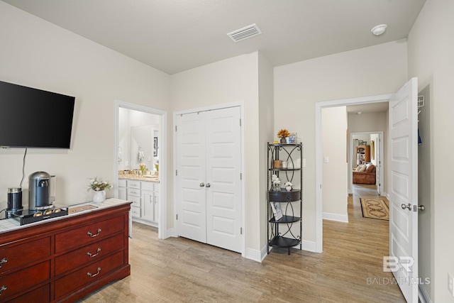 bedroom with ensuite bath, a closet, and light hardwood / wood-style flooring