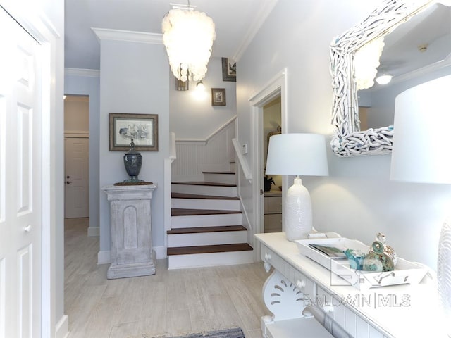 stairs featuring wood finished floors, a chandelier, and crown molding