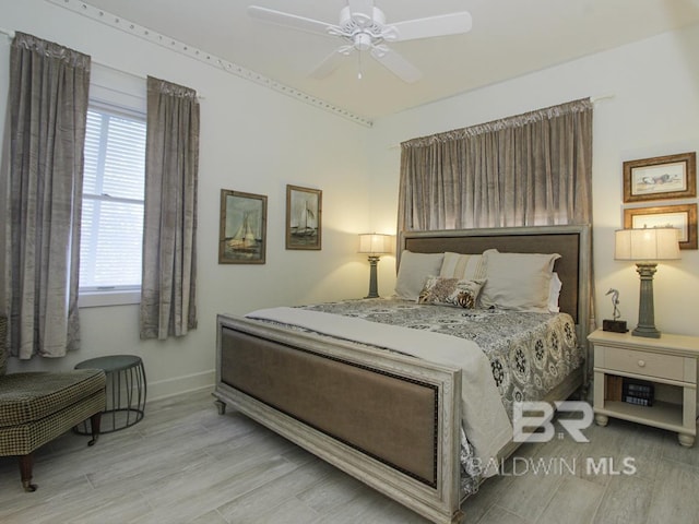 bedroom featuring wood finished floors, baseboards, and ceiling fan