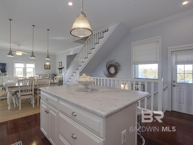 kitchen featuring dark wood finished floors, a healthy amount of sunlight, white cabinets, and ornamental molding