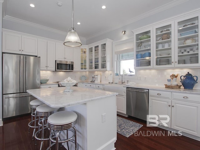 kitchen with white cabinets, dark wood-style floors, appliances with stainless steel finishes, and ornamental molding