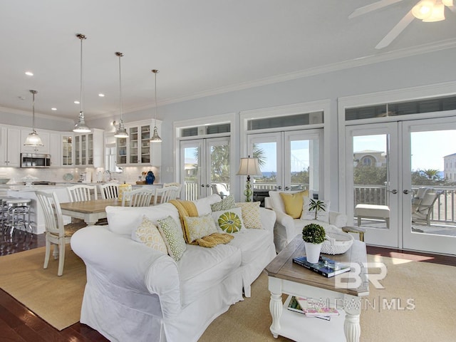 living area with dark wood-type flooring, a ceiling fan, recessed lighting, french doors, and crown molding