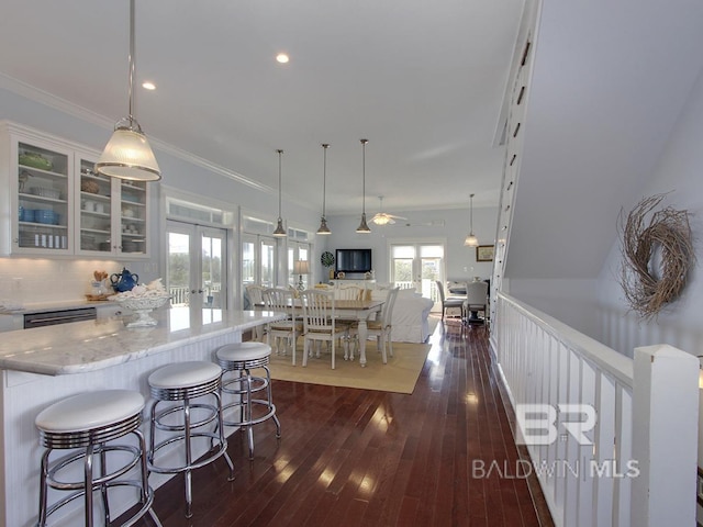 kitchen with dark wood-style flooring, ornamental molding, white cabinets, glass insert cabinets, and french doors