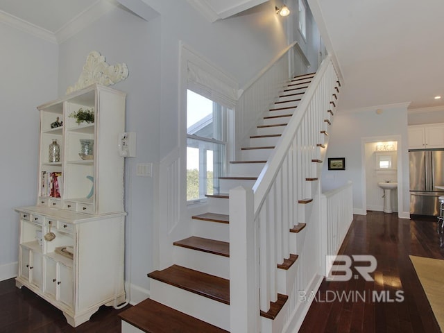 stairway featuring wood finished floors, baseboards, and ornamental molding