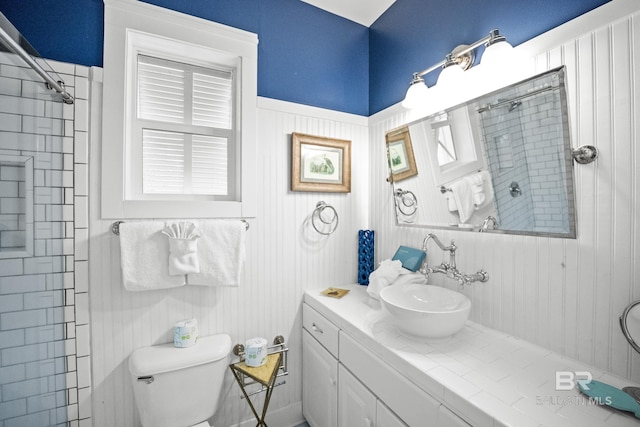 full bath featuring toilet, vanity, and a tile shower