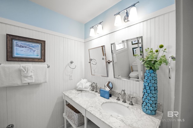 bathroom featuring double vanity, toilet, and a sink