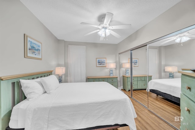 bedroom featuring a closet, light hardwood / wood-style floors, a textured ceiling, and ceiling fan
