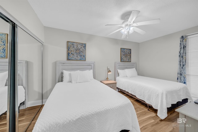 bedroom with wood-type flooring, ceiling fan, and a closet