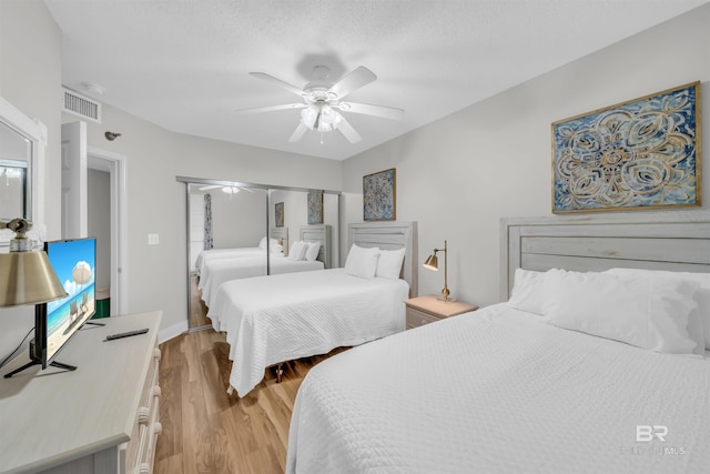 bedroom featuring ceiling fan, a textured ceiling, a closet, and light wood-type flooring