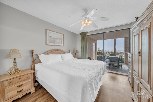 bedroom with access to exterior, a textured ceiling, wood-type flooring, and ceiling fan