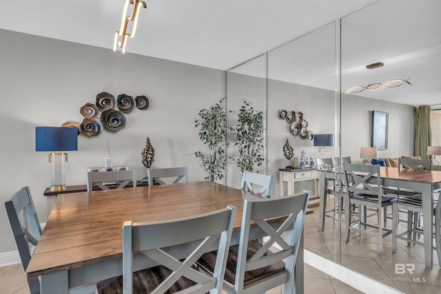 dining space with track lighting, light tile patterned floors, and a textured ceiling