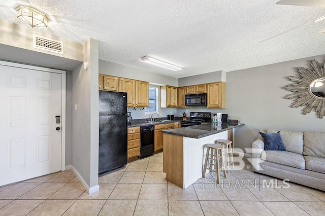 kitchen with visible vents, a peninsula, black appliances, a kitchen bar, and a sink