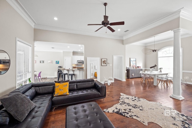 living room featuring ceiling fan, dark wood-type flooring, crown molding, and decorative columns