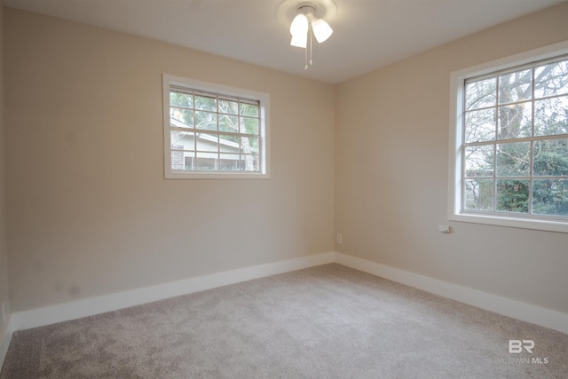 spare room with ceiling fan, a healthy amount of sunlight, and light colored carpet