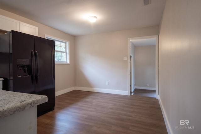 kitchen featuring white cabinets, light stone countertops, black fridge with ice dispenser, and dark hardwood / wood-style flooring