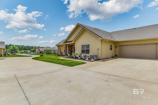 view of front of house with a garage, a front yard, and central AC unit