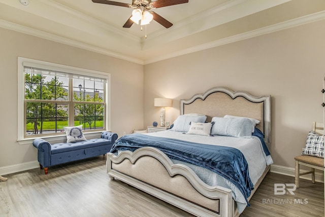 bedroom with hardwood / wood-style floors, a tray ceiling, ornamental molding, and ceiling fan