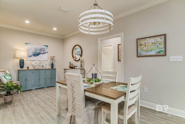 dining area with ornamental molding, hardwood / wood-style floors, and an inviting chandelier