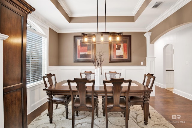 dining space with a tray ceiling, ornamental molding, and dark hardwood / wood-style floors