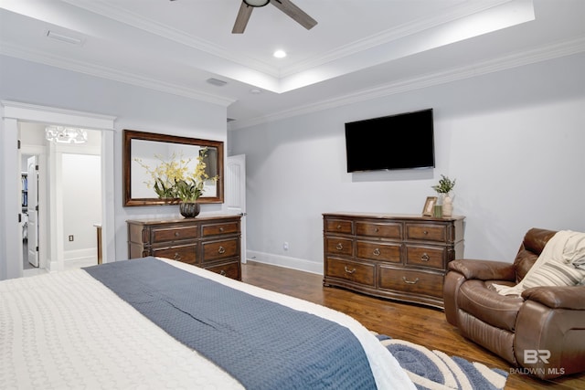 bedroom with dark hardwood / wood-style floors, ceiling fan, ornamental molding, and a tray ceiling