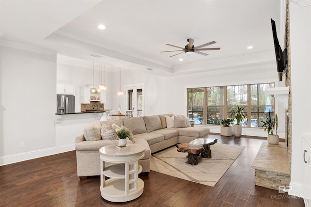 living room with crown molding, ceiling fan, dark hardwood / wood-style flooring, and a tray ceiling