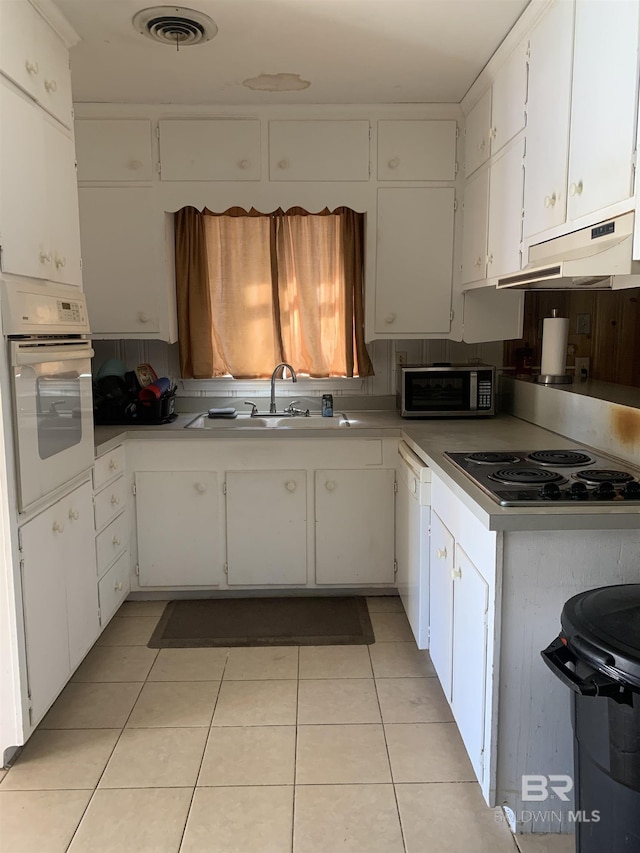 kitchen featuring sink, white cabinetry, light tile patterned floors, white appliances, and backsplash