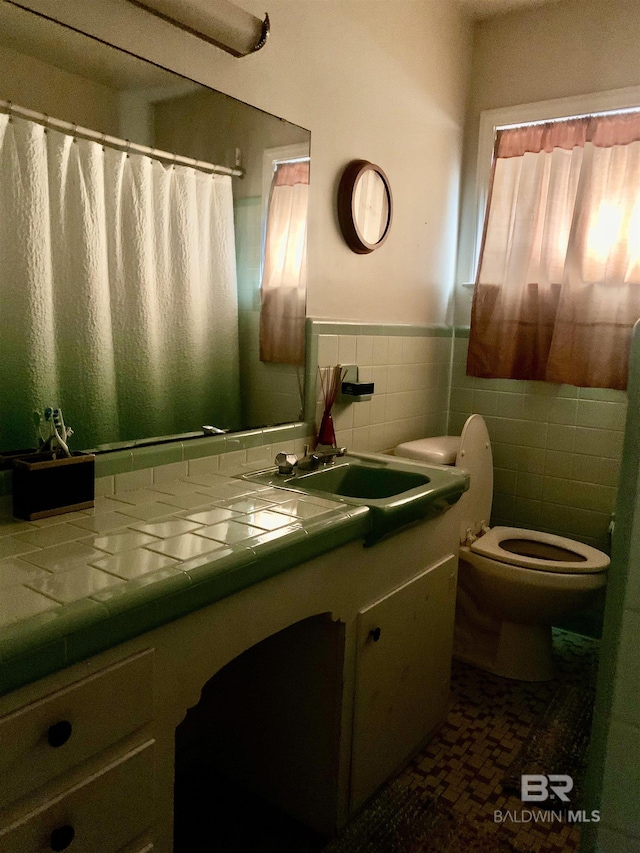 bathroom featuring vanity, toilet, and tile walls