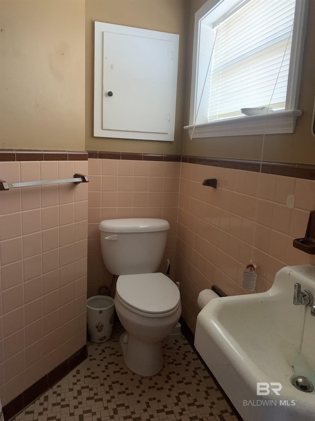 bathroom with toilet, tile patterned flooring, and tile walls