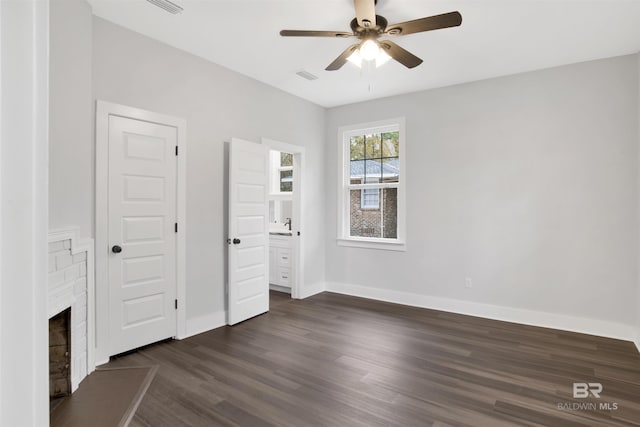 unfurnished bedroom with dark wood-type flooring, ceiling fan, and a fireplace