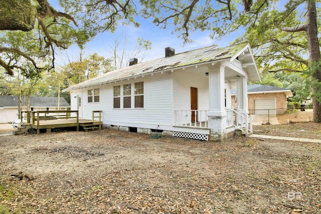 rear view of property featuring a wooden deck and a garage