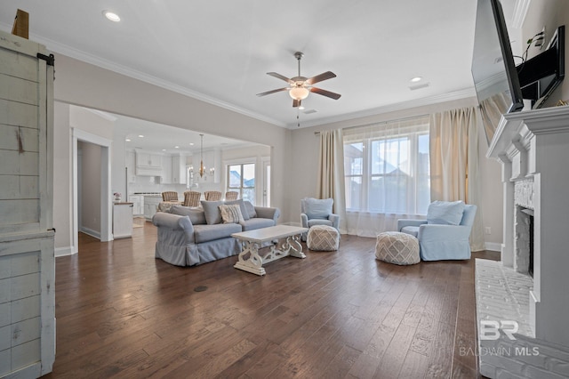 living room with crown molding, dark hardwood / wood-style flooring, a healthy amount of sunlight, and a fireplace