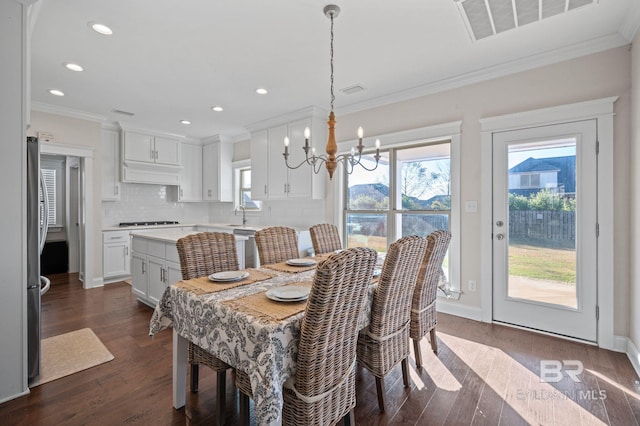 dining room featuring sink, a notable chandelier, dark hardwood / wood-style flooring, and crown molding