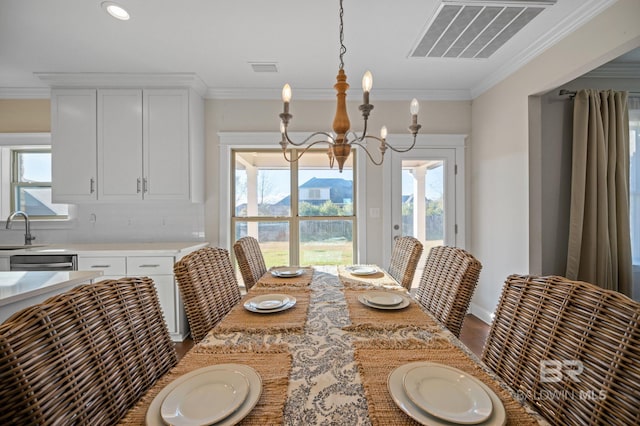 dining space with sink, ornamental molding, and an inviting chandelier